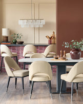 Contemporary dining room featuring a marble table and cream chairs with black and silver legs, under a modern light fixture.