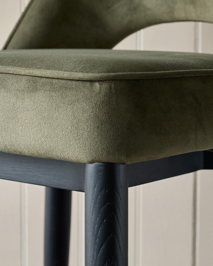 Close-up of an olive green chair with black legs, showcasing its textured fabric and sleek design.