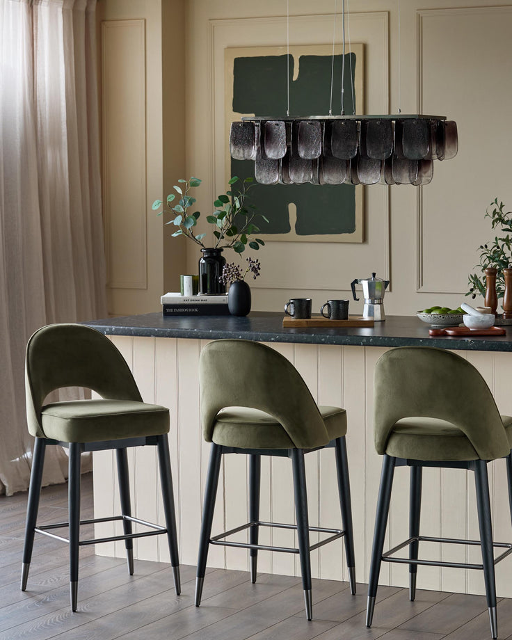Three stylish green velvet bar stools with black legs, set at a kitchen island, creating a modern, elegant look.
