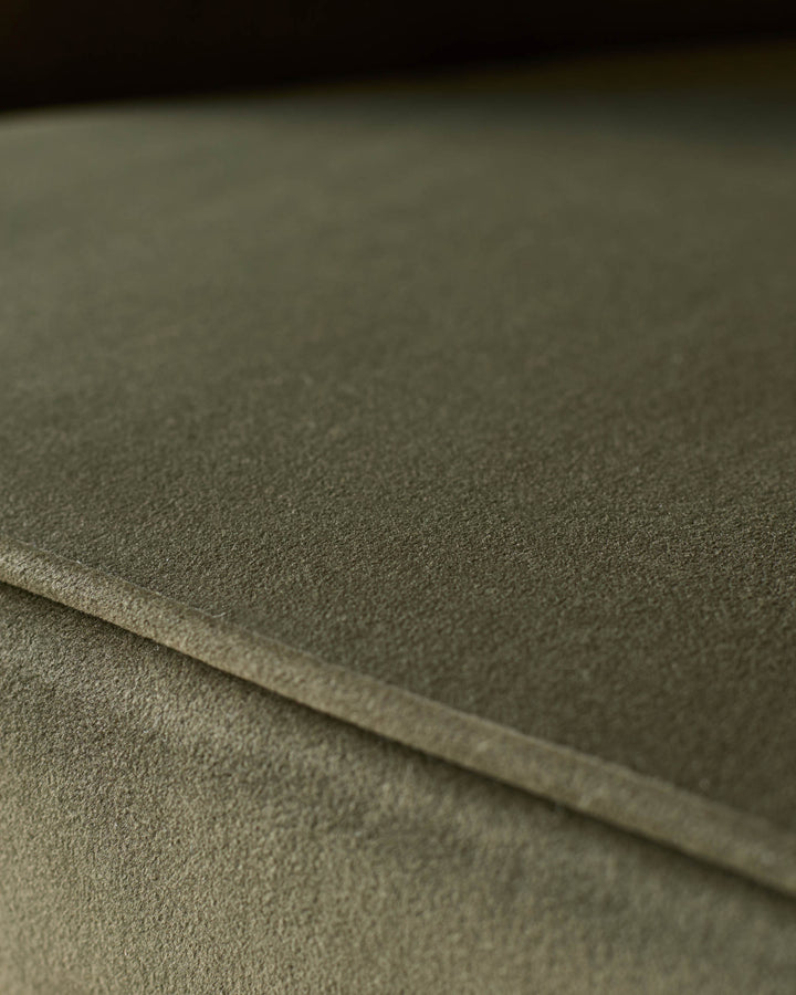 Close-up of a green fabric sofa or armchair. The texture of the upholstery is visible.