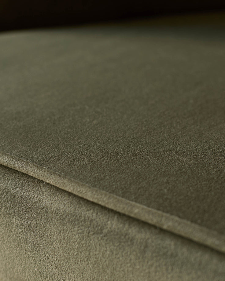 Close-up of a green fabric sofa or armchair. The texture of the upholstery is visible.