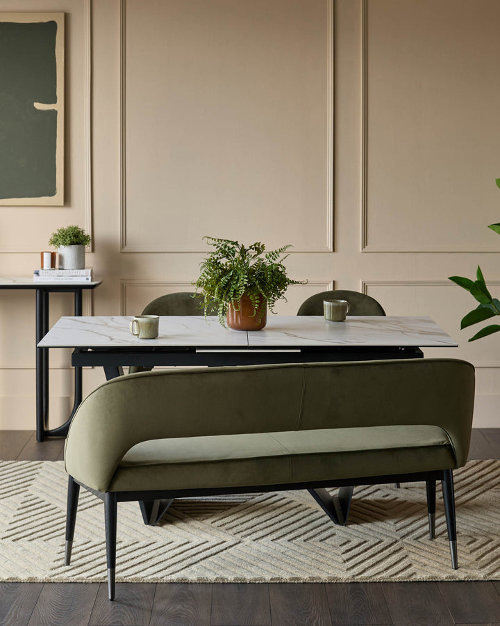A dining space featuring a marble table, green velvet bench, and elegant decor. Perfect for modern homes.
