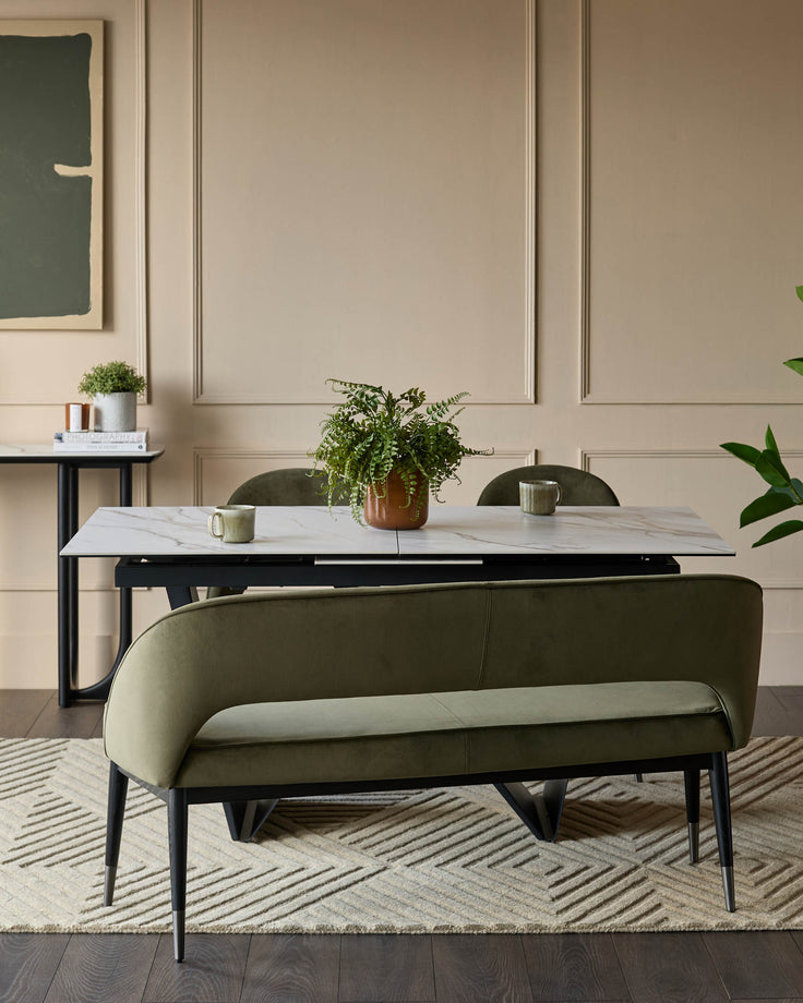 A dining space featuring a marble table, green velvet bench, and elegant decor. Perfect for modern homes.