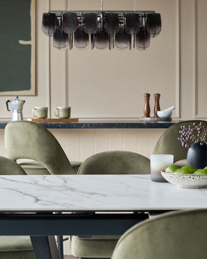 Dining room furniture includes green chairs, a marble table and a statement light fixture.