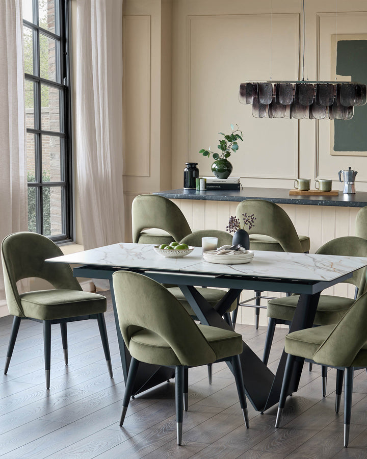 A marble dining table and six green velvet chairs furnish this modern dining space with a neutral, elegant backdrop.