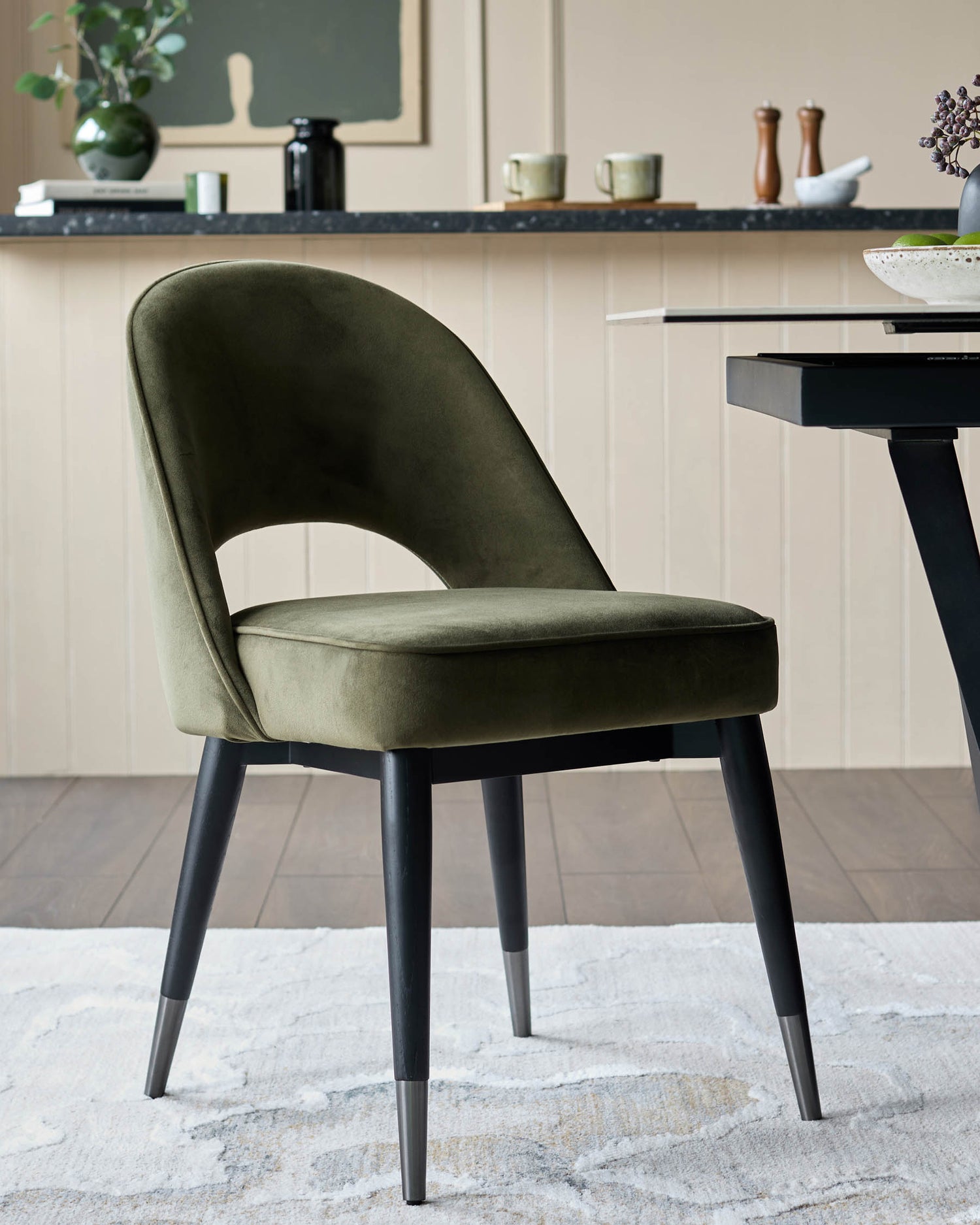 Olive green velvet chair with black legs. Modern design and stylish upholstery for a dining room or lounge area.