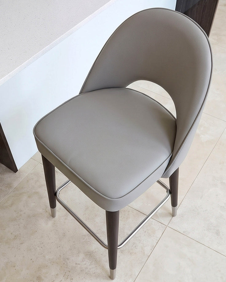 Clover light grey faux-leather bar stool with curved backrest, dark wooden legs, and footrest, photographed from above.
