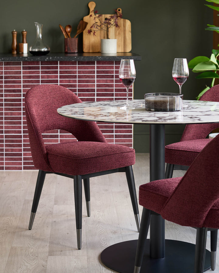 Burgundy chairs around a round marble table. Chic dining furniture with a contemporary design.