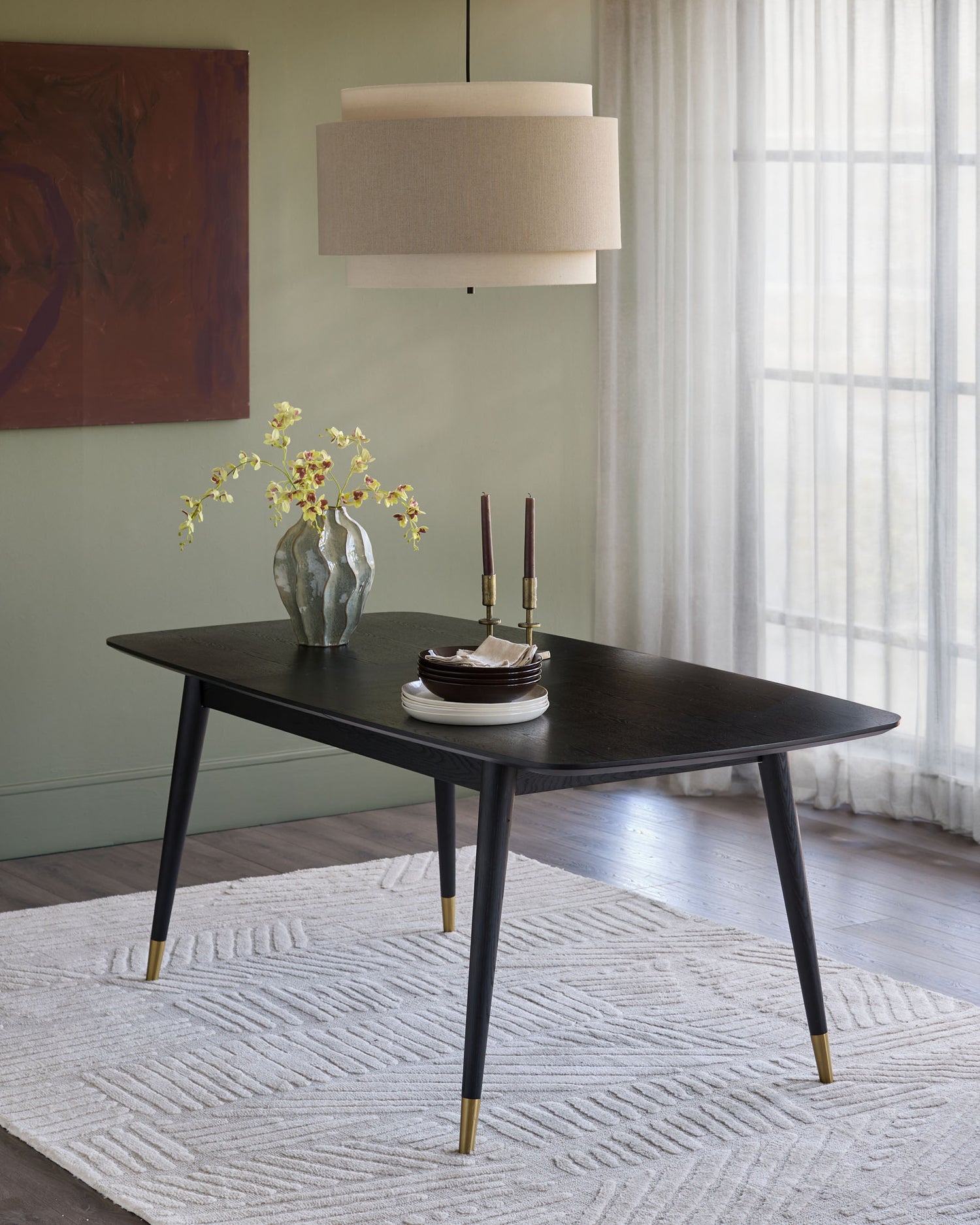Black extending dining table with tapered legs and brass feet, displayed in a styled dining room setting.