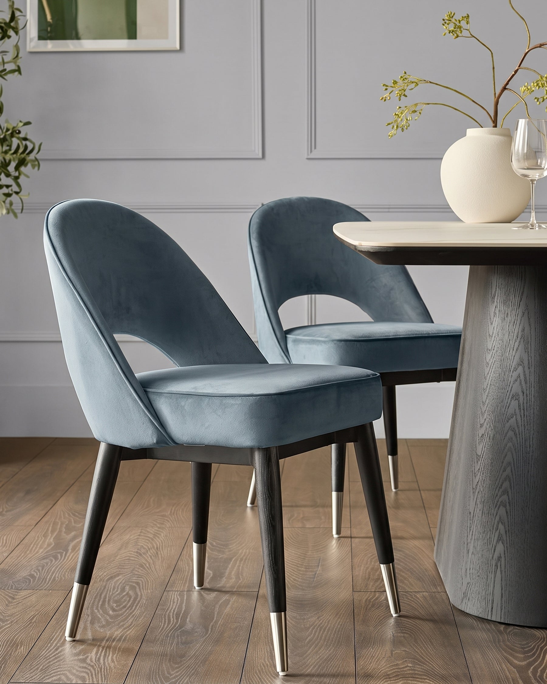 Clover blue velvet dining chair with curved backrest and stainless steel leg caps, shown at table.