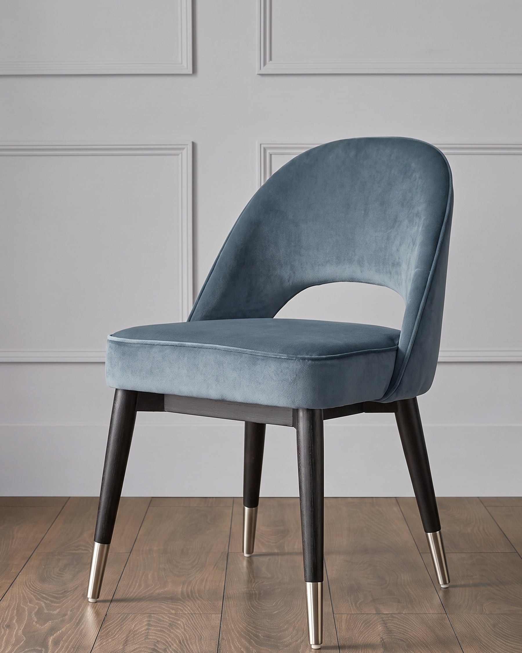 Blue velvet dining chair with curved back, dark wooden legs, and stainless steel cap feet.