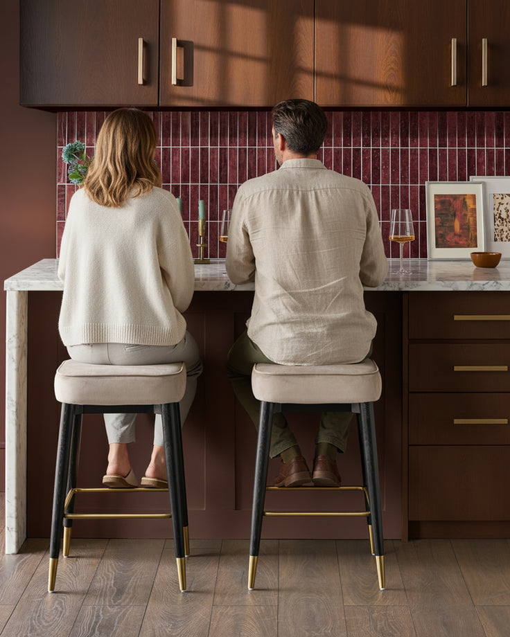 Champagne velvet backless bar stools with black legs and brass footrests, shown in a kitchen setting.