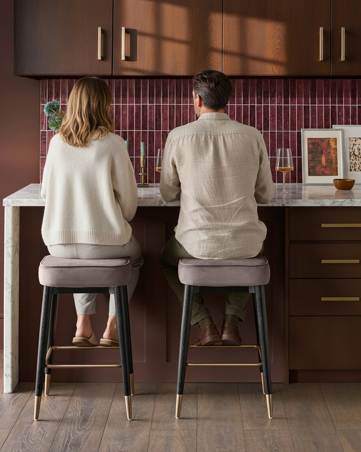 Mocha velvet backless bar stools with black legs and brass foot rails, shown in a kitchen setting.