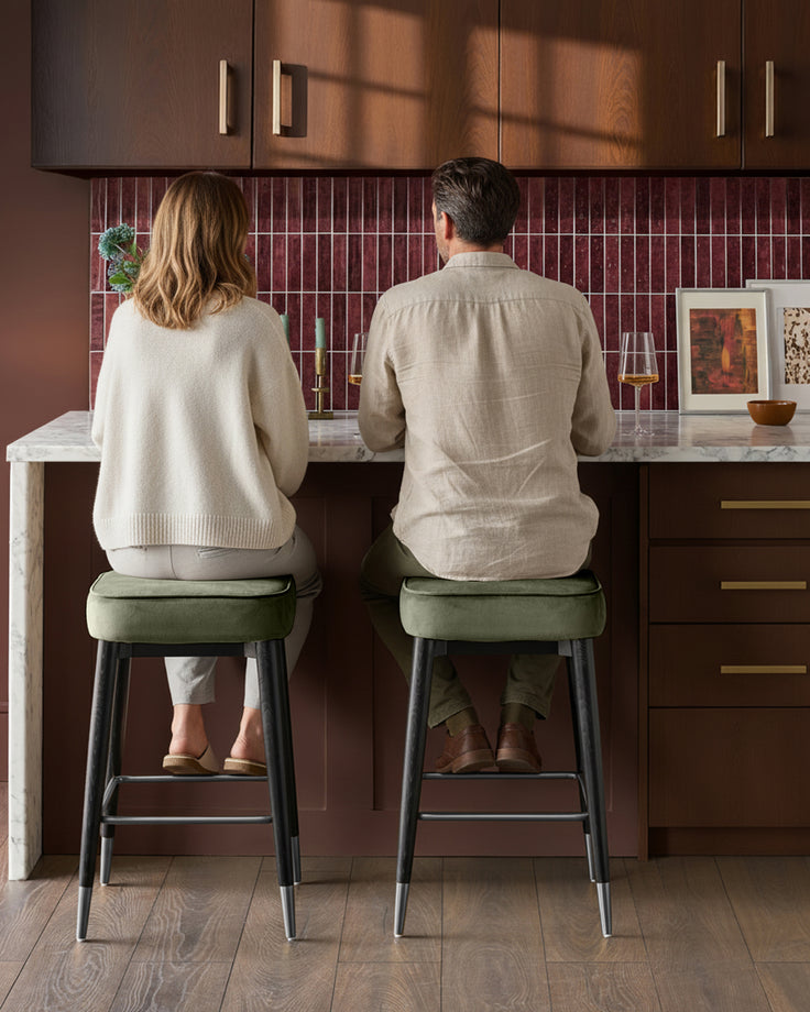 Clover velvet backless bar stools in olive green with black metal legs, shown as pair at kitchen counter.