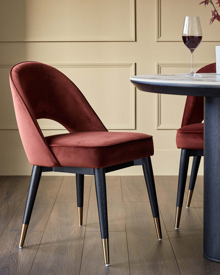 A stylish dining set featuring luxurious velvet chairs with sleek, tapered legs and gold accents.