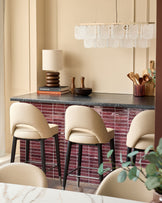 Stylish kitchen with breakfast bar. Bar stools upholstered in cream with dark wood legs & a unique glass chandelier overhead.