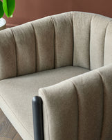 Stylish, taupe-coloured armchair with vertical panelling detail and sleek black armrests. Contemporary design for modern living.