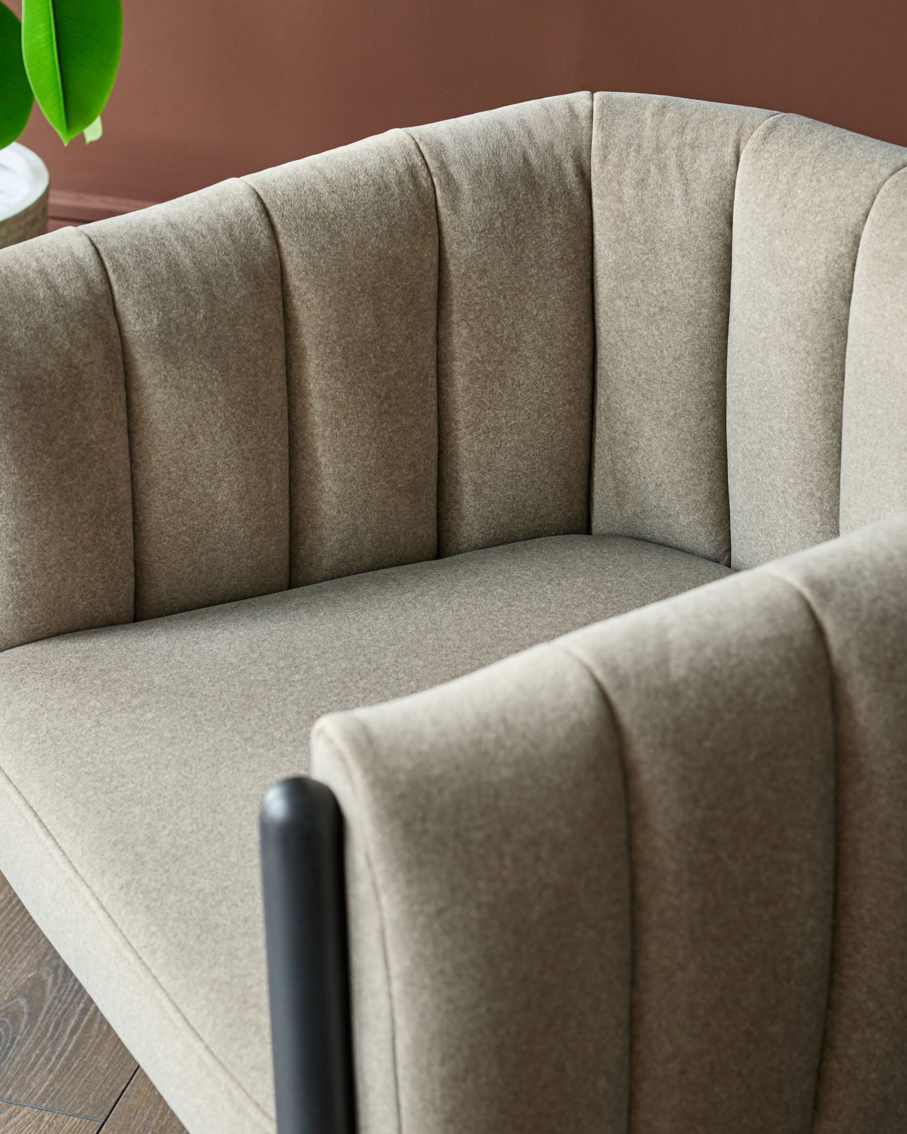 Stylish, taupe-coloured armchair with vertical panelling detail and sleek black armrests. Contemporary design for modern living.