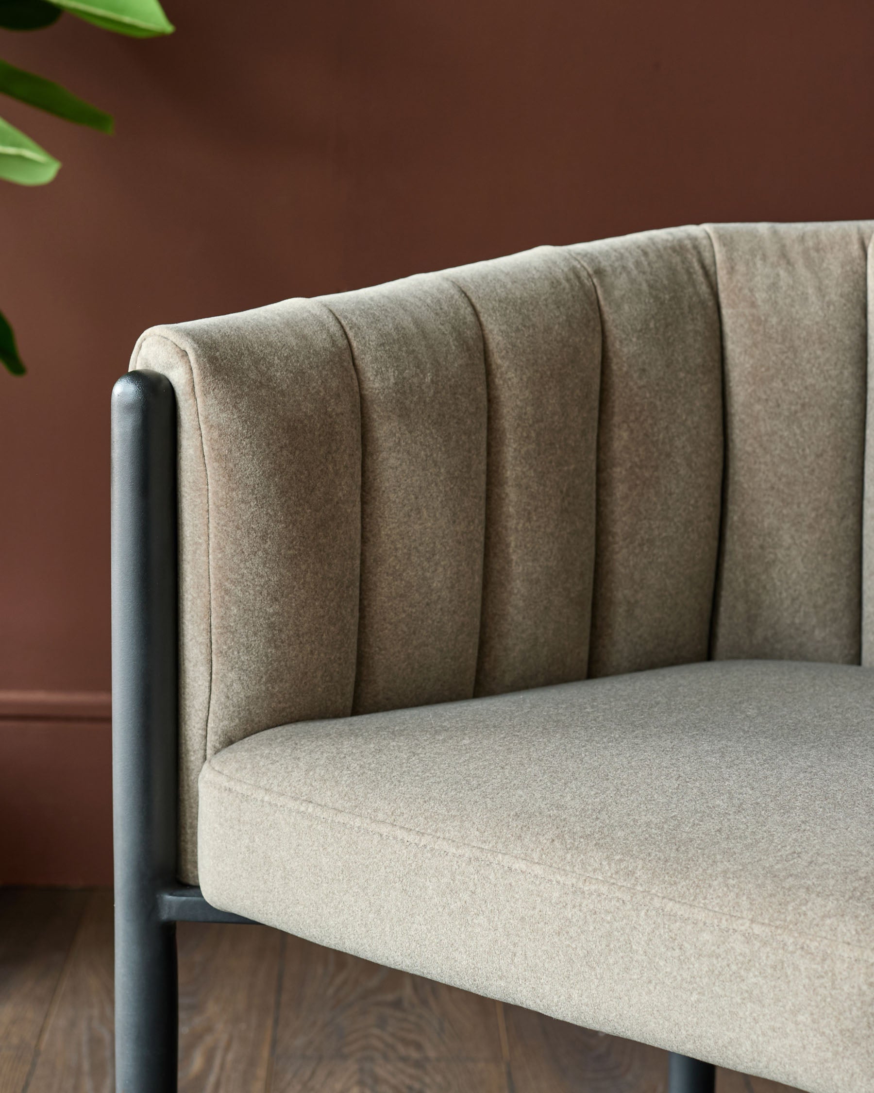 Close up of a modern chair with a grey fabric seat and backrest, and a black metal frame.