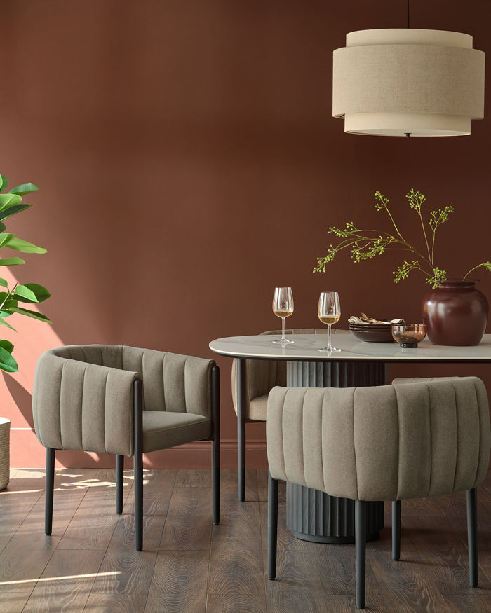 A dining setting showcasing modern chairs with black legs and a marble-look table, complemented by a neutral pendant light.