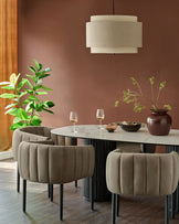 A dining area featuring modern chairs, an oval table, neutral coloured lamp, and a stylish dark wooden floor.