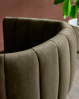 Close-up of a stylish, fluted, curved armchair in a muted, earthy tone, offering a tactile and inviting seating option.