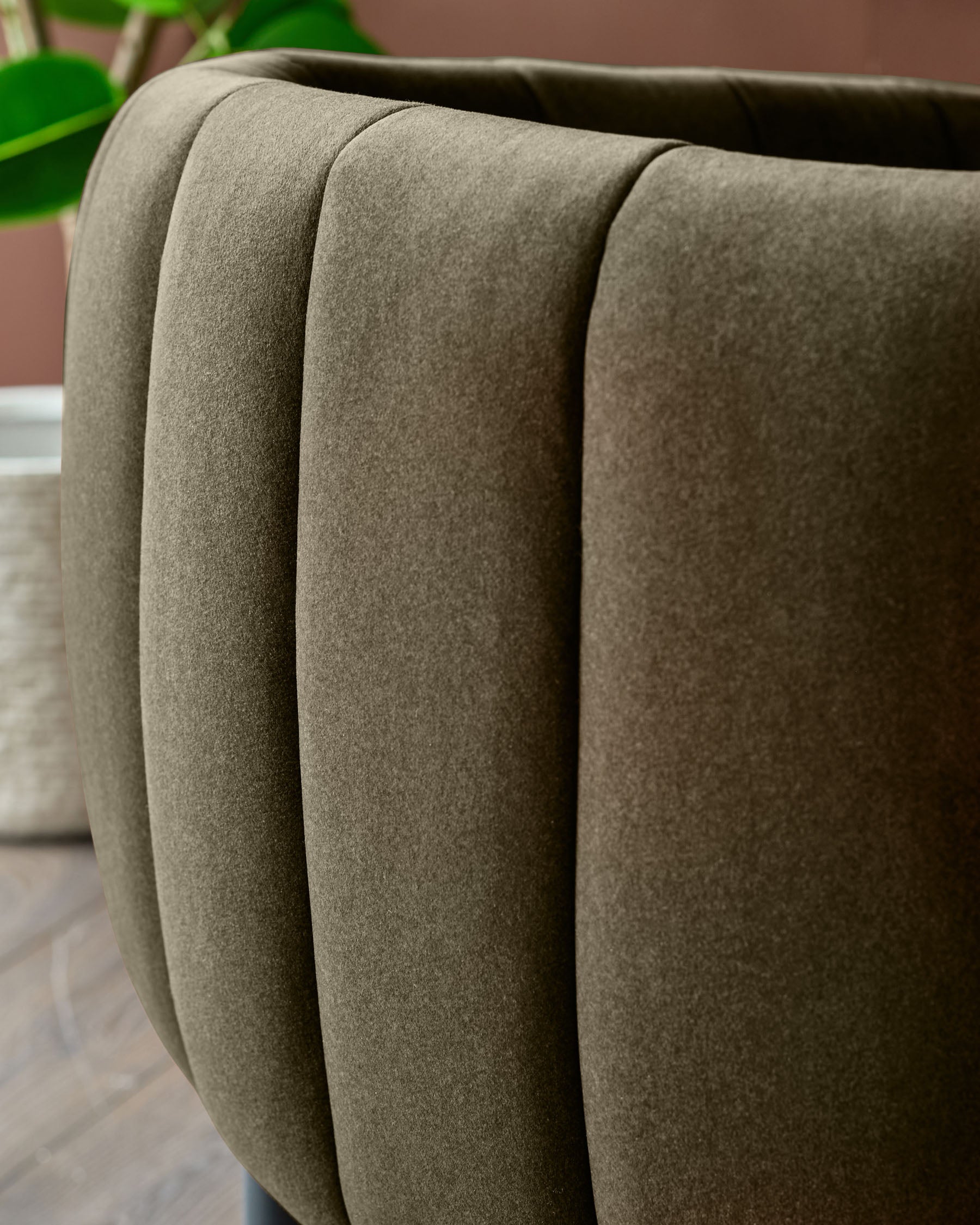Close-up of a modern olive green velvet ribbed chair back, showcasing its texture and design.