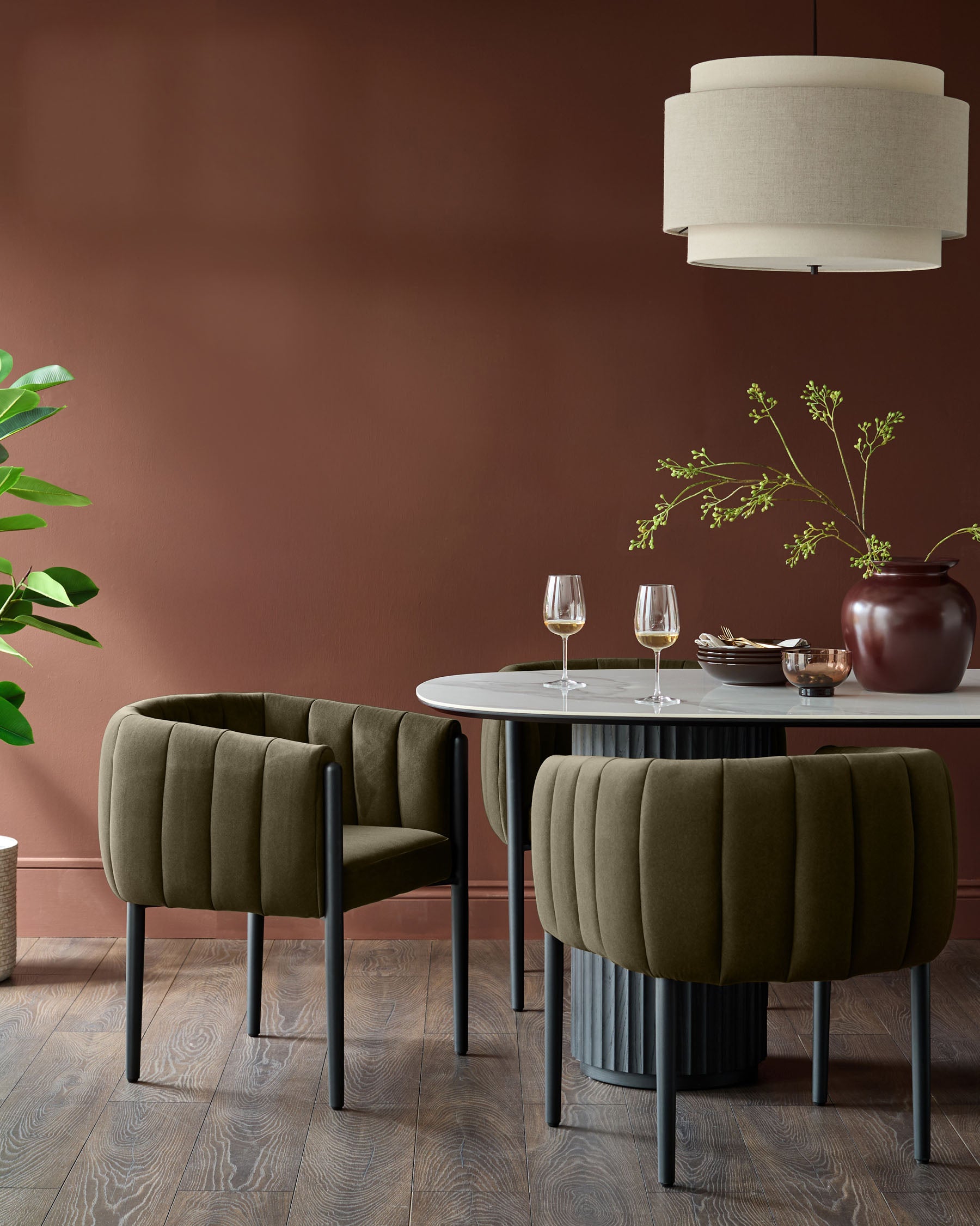A modern dining set featuring a marble table and two stylish, olive-green velvet chairs with black legs.