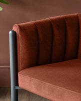 Close-up of a stylish, rust-coloured upholstered chair with a fluted back and matte black frame. Modern furniture detail.