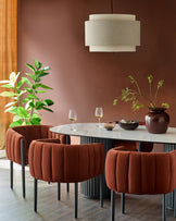 Dining area with upholstered chairs, marble table, statement light fixture and house plant in a modern, stylish space.