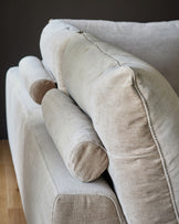 Colette right-hand corner chaise sofa in mink fabric, showing curved armrest and cylindrical bolster pillows from a side angle.