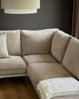 Mink fabric right-hand corner chaise sofa with cushioned back pillows and dark legs, styled in a modern living room setting.