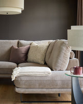 Mink fabric right-hand corner chaise sofa with decorative pillows and throw blanket in a modern living room setting.