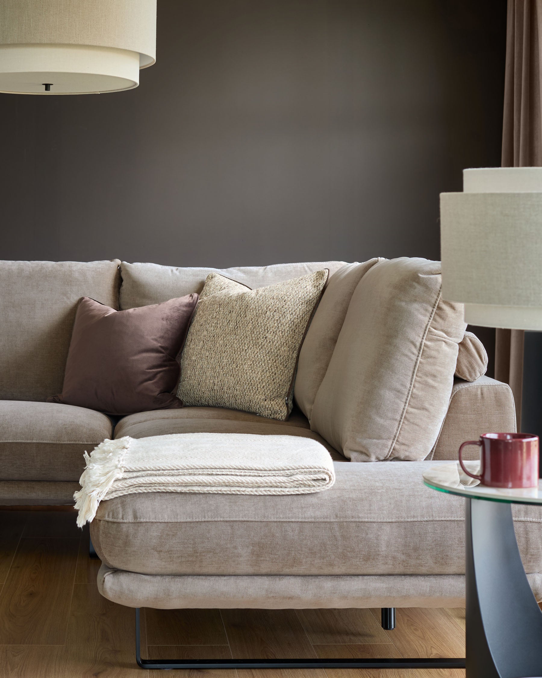 Mink fabric right-hand corner chaise sofa with decorative pillows and throw blanket in a modern living room setting.