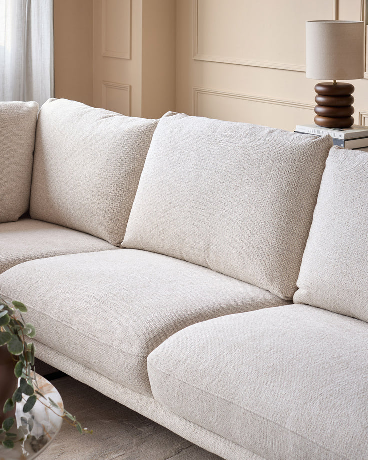 Colette left-hand corner chaise sofa in natural fabric, shown from a side angle displaying plush cushions and modern silhouette.