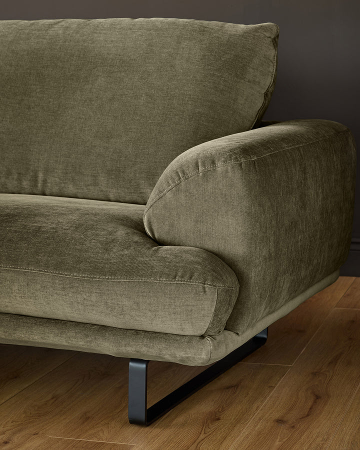 Colette right-hand corner chaise sofa in olive green fabric with metal legs, shown from a side angle on wooden flooring.