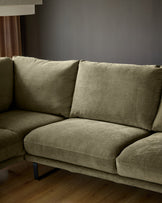 Olive green fabric left-hand corner chaise sofa with black legs, styled with patterned pillows in a modern living room.