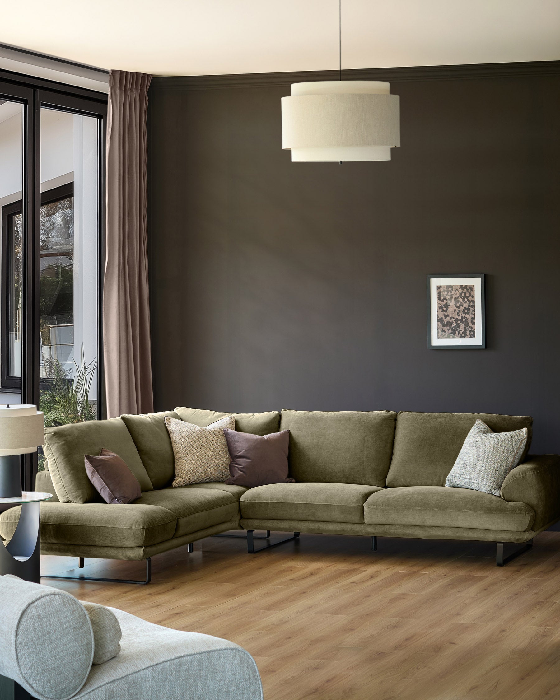 Colette left-hand corner chaise sofa in olive green fabric, displayed in a modern living room setting with dark walls.