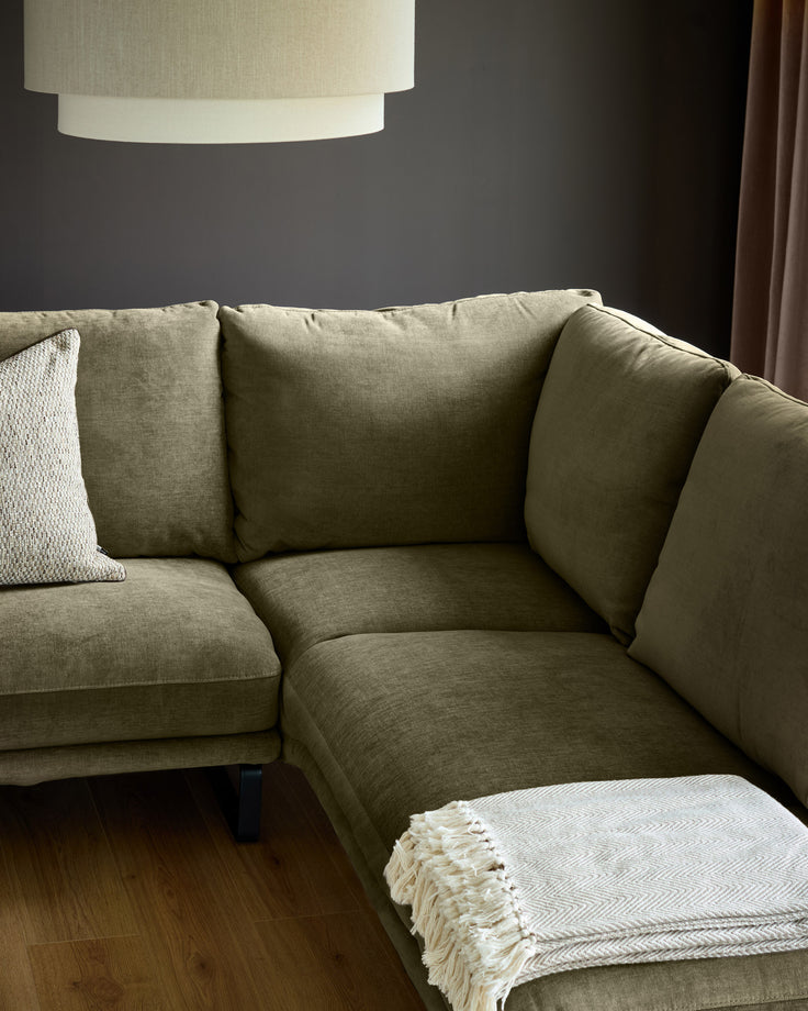 Olive green fabric right-hand corner chaise sofa with cushioned back and arms, displayed in a modern living room setting.