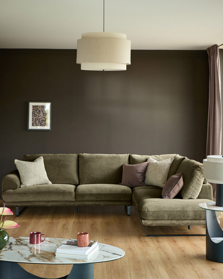 Olive green corner chaise sofa with right-hand chaise, decorative pillows, metal legs, in modern living room setting.