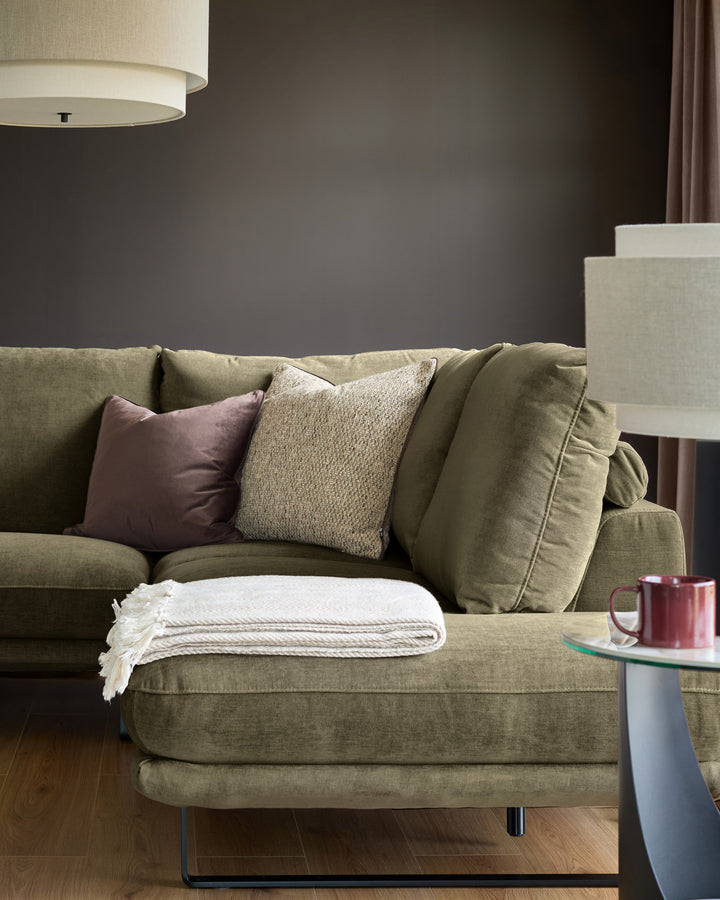 Colette right-hand corner chaise sofa in olive green fabric, styled with decorative pillows and throw blanket in a modern living room setting.
