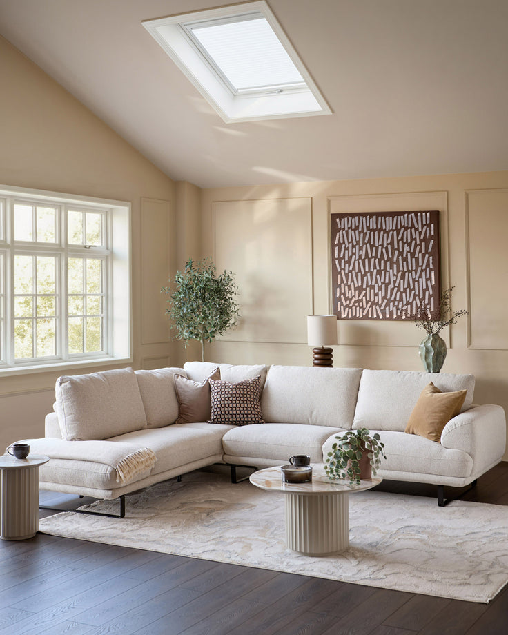 Colette left-hand corner chaise sofa in natural fabric, displayed in a bright living room with skylight and large windows.