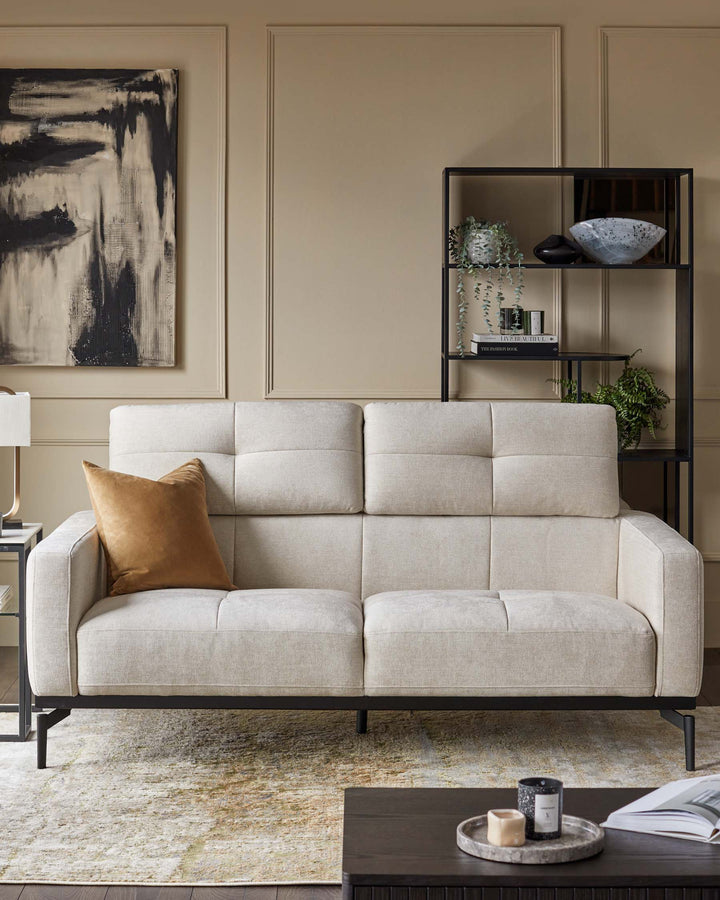 A modern living room featuring a stylish sofa, black metal shelving unit, and a coffee table with decorative objects.