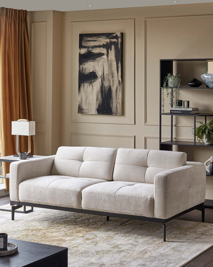 Stylish light-coloured sofa with a black metal frame, complemented by a modern black shelving unit.