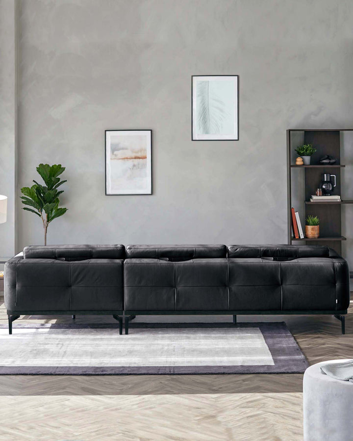 A sleek black leather sofa with tufted design, paired with a modern bookshelf and decorative accents against a neutral wall.