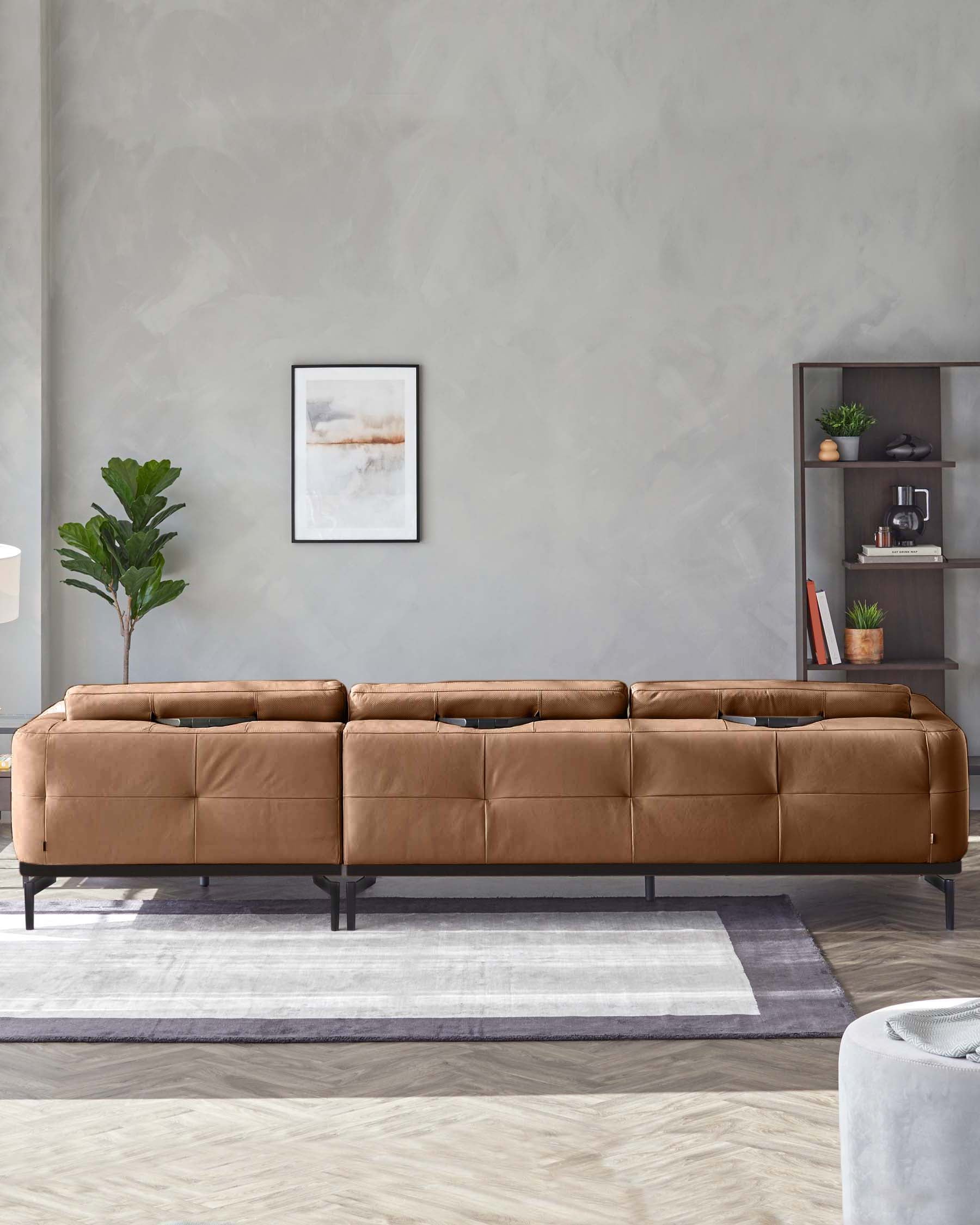 A brown leather sofa stands on a light-grey rug in front of a grey wall with artwork and shelving.