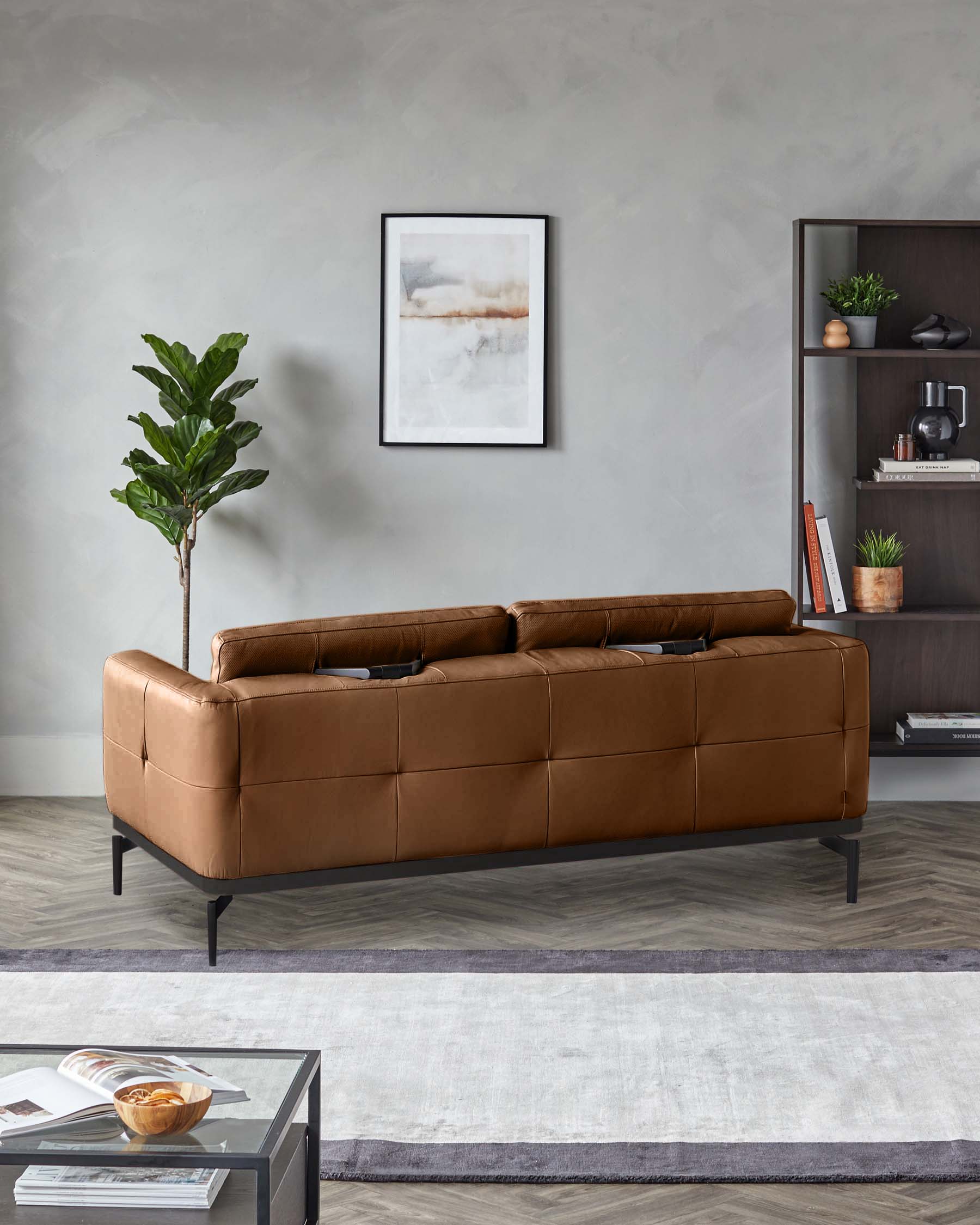 A stylish brown leather sofa with sleek, black metal legs, complemented by a modern bookcase and coffee table.