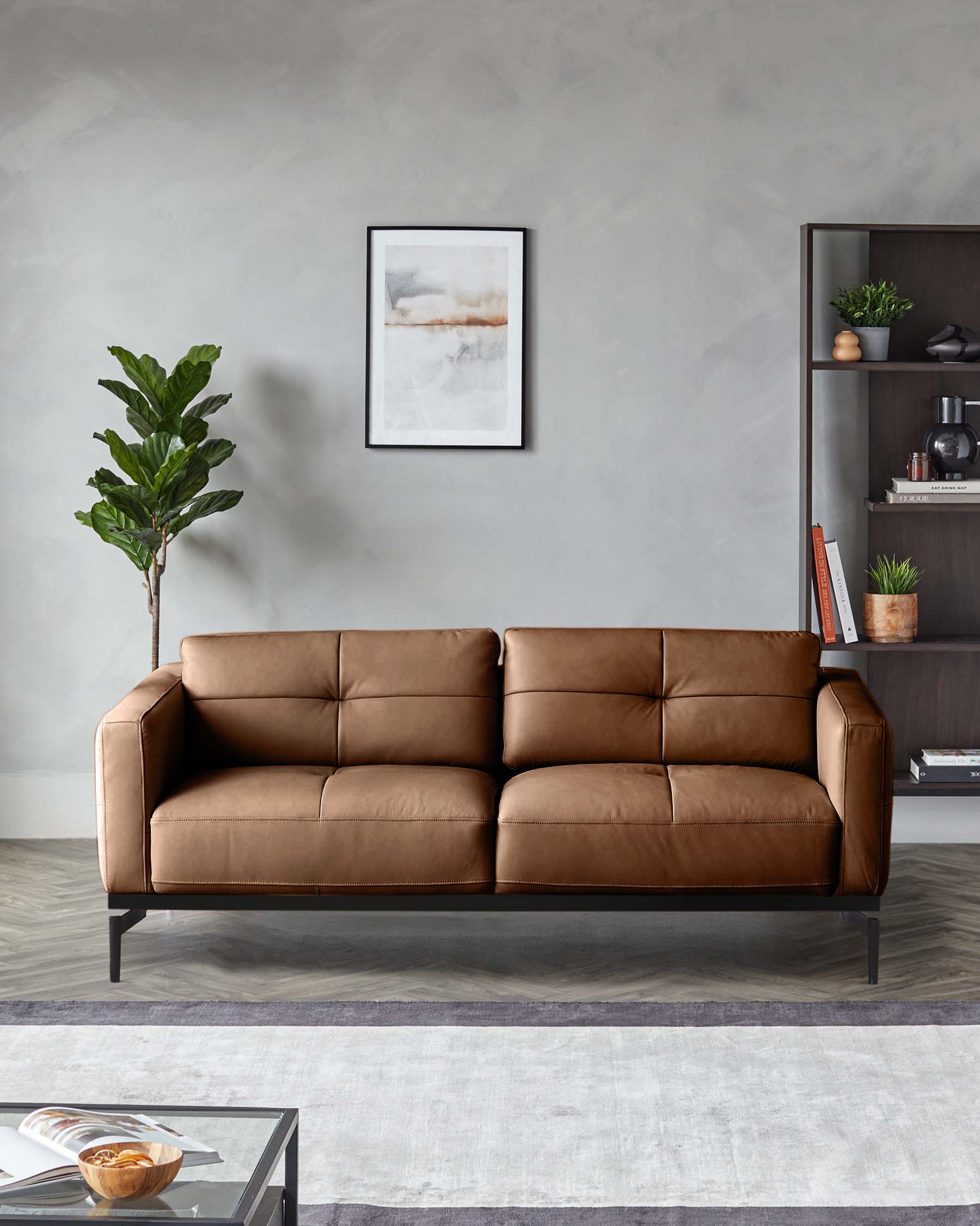 A stylish brown leather sofa takes centre stage in this modern living space, accompanied by a dark wood shelving unit and a lush plant.
