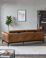 A tan leather sofa with a modern black frame, showcased in a styled living room setting.