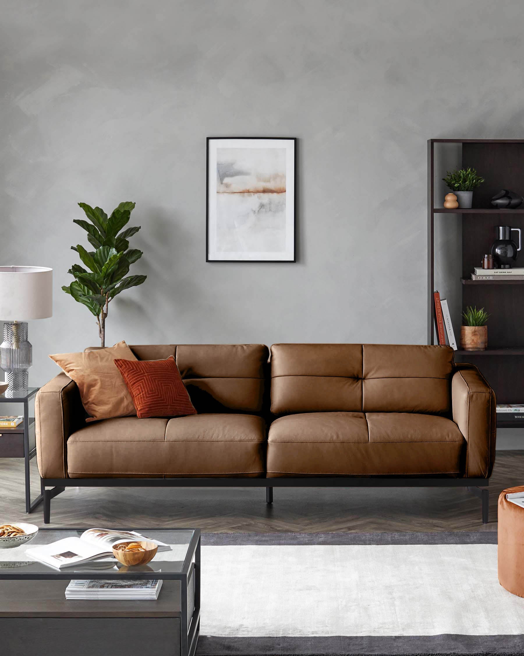 Stylish, leather sofa with scatter cushions. Accompanied by a dark bookcase and glass side table, in a modern living room.
